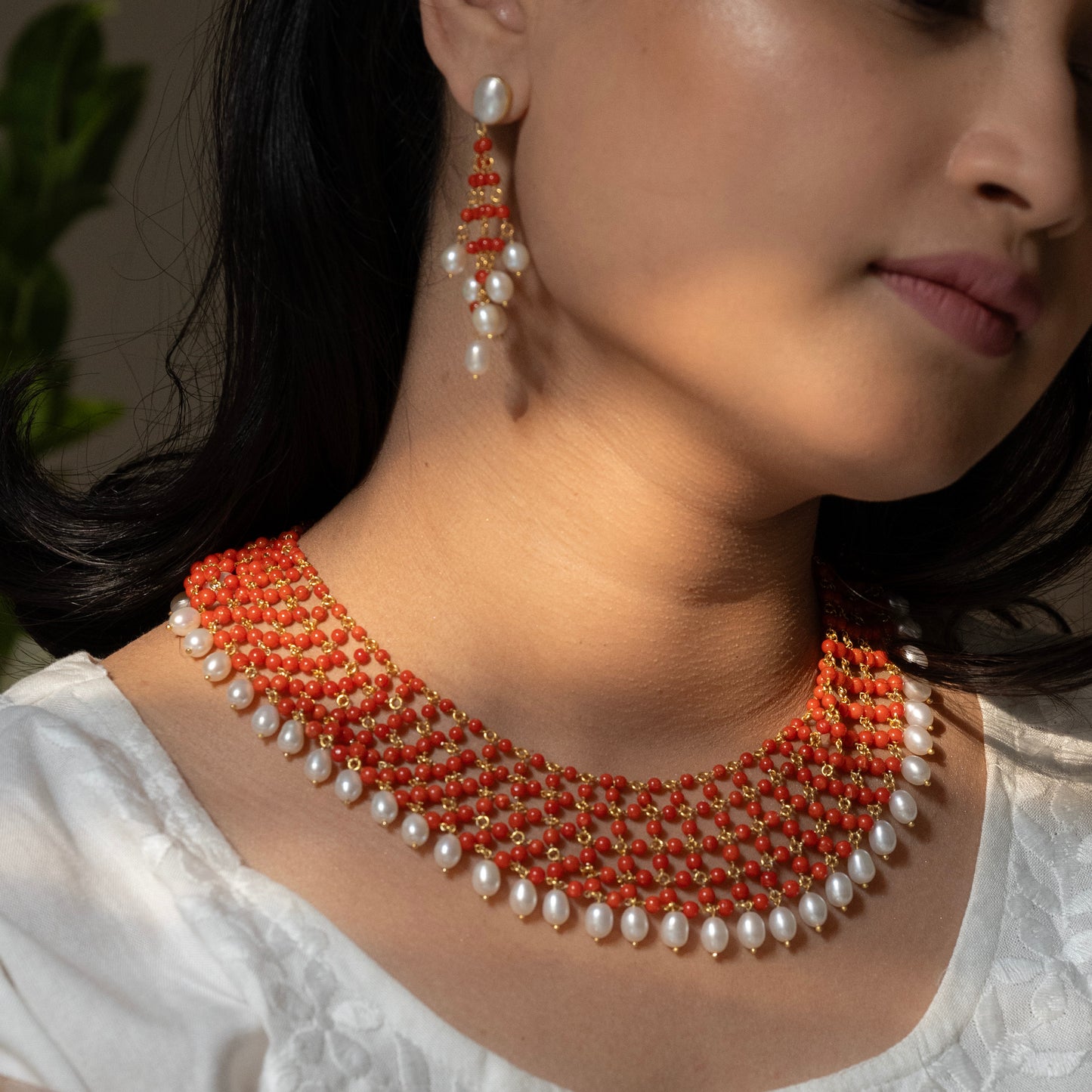 Statement coral necklace with dangling pearl stones, crafted in sterling silver with a gold finish. The necklace features vibrant coral and elegant pearls, creating a bold and luxurious design