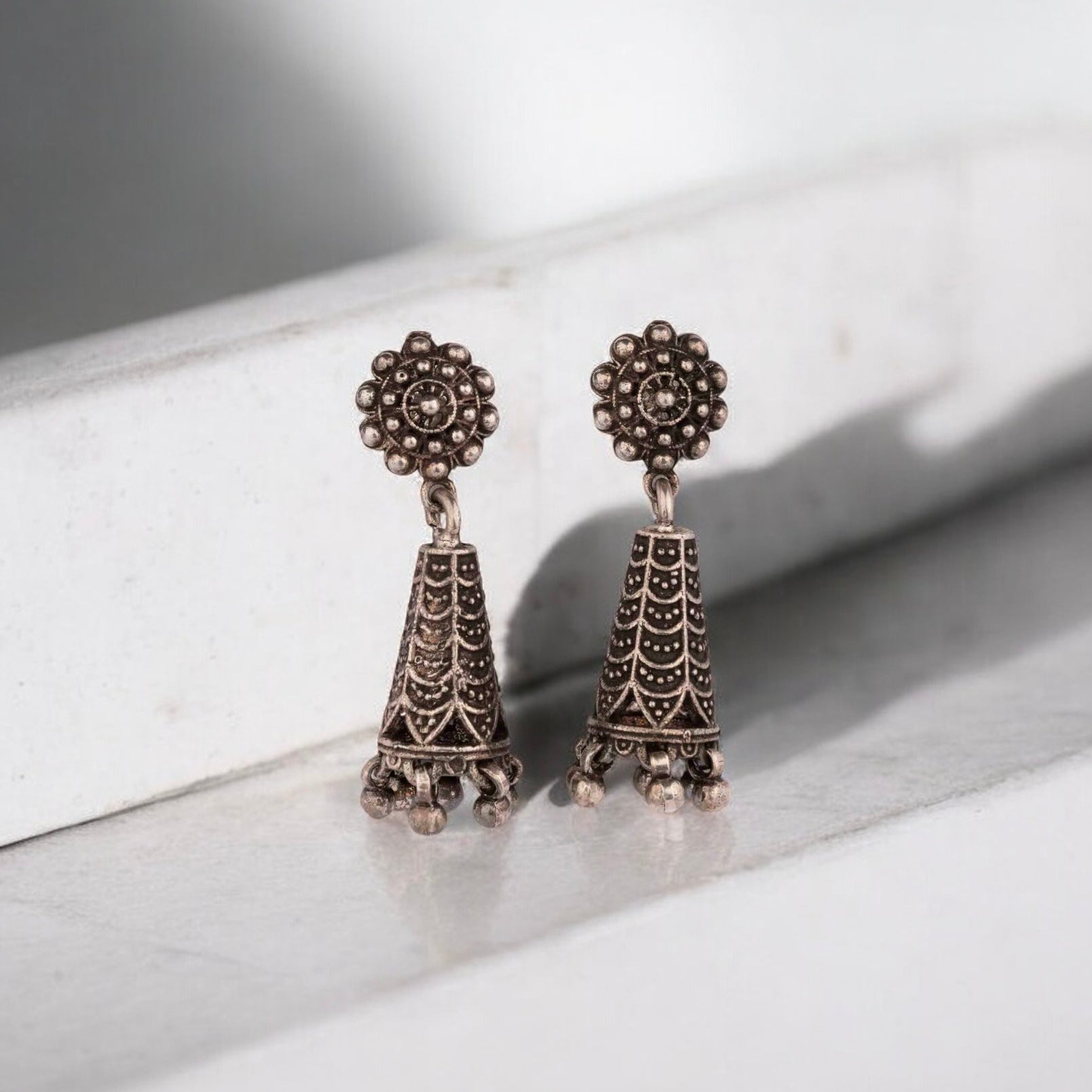 Intricately designed silver oxidized jhumka earrings with a traditional and vintage-inspired charm.