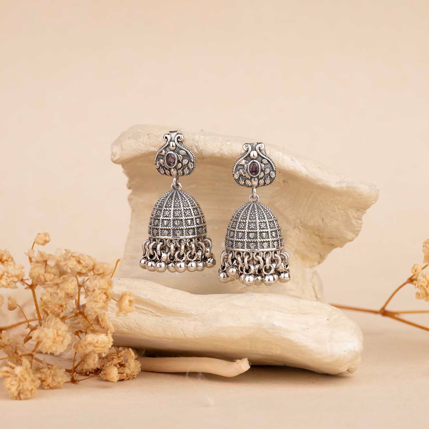 Silver earrings with gemstones on a natural stone background