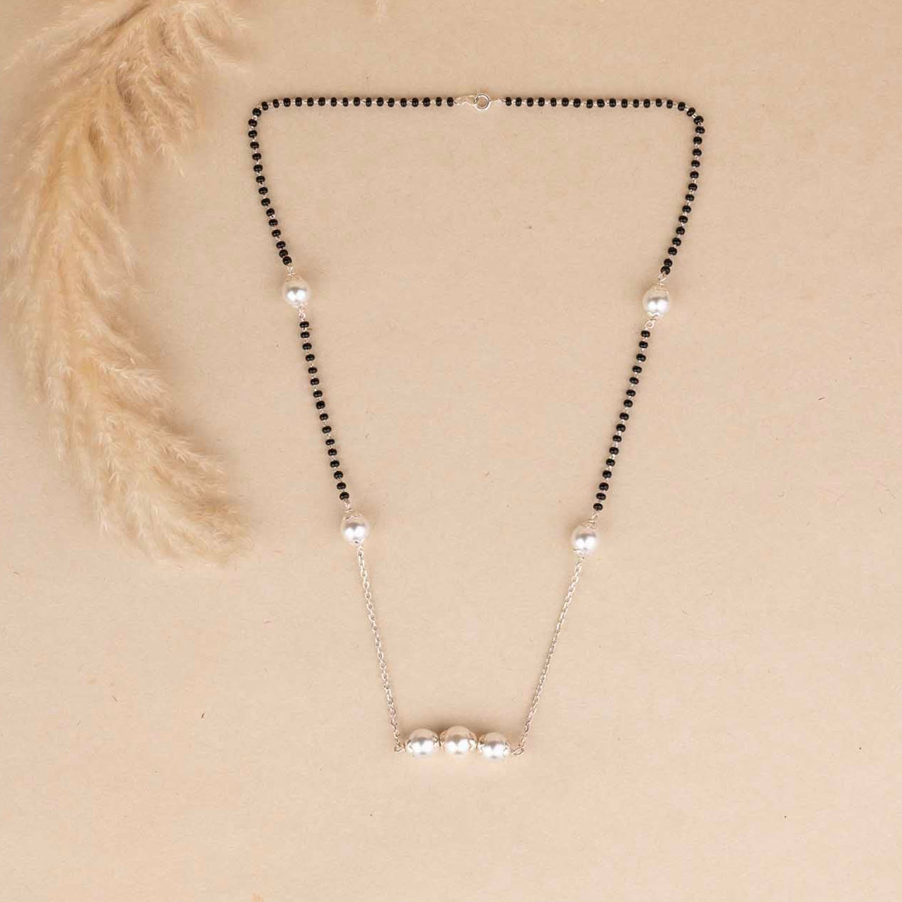 Necklace with black beads and silver pendants on a beige background