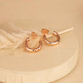 Rose gold hoop earrings on a beige background