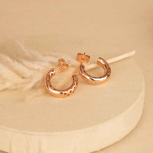 Rose gold hoop earrings on a beige background