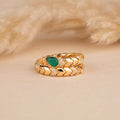 Gold ring with green gemstone on a beige fur background