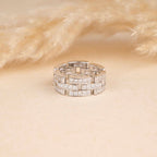 Silver ring with embedded stones on a beige background