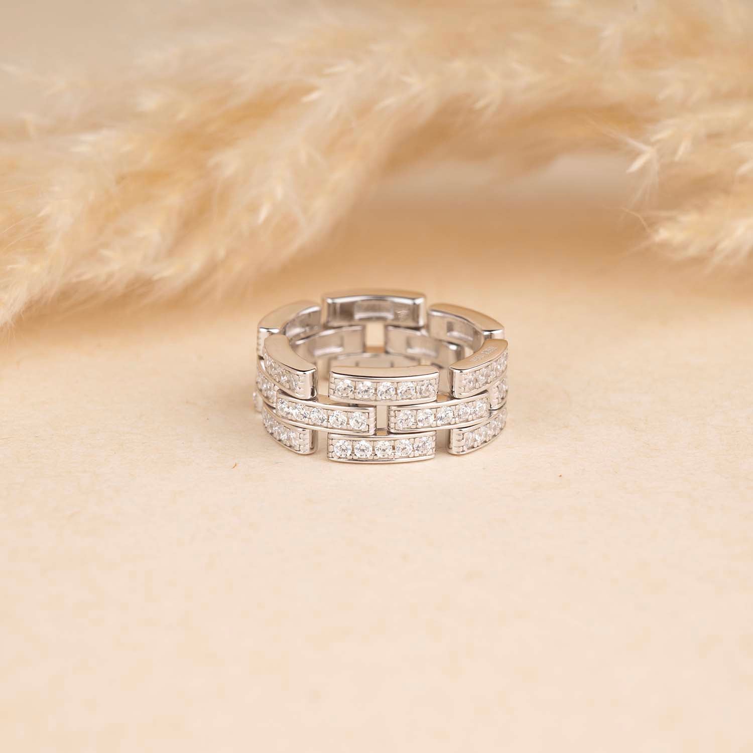 Silver ring with embedded stones on a beige background