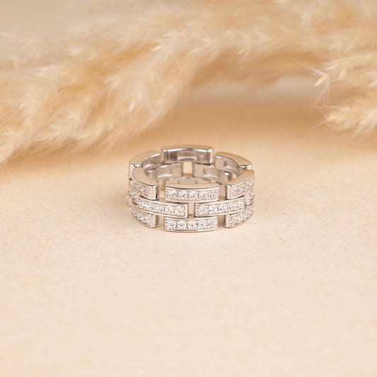 Silver ring with embedded stones on a beige background