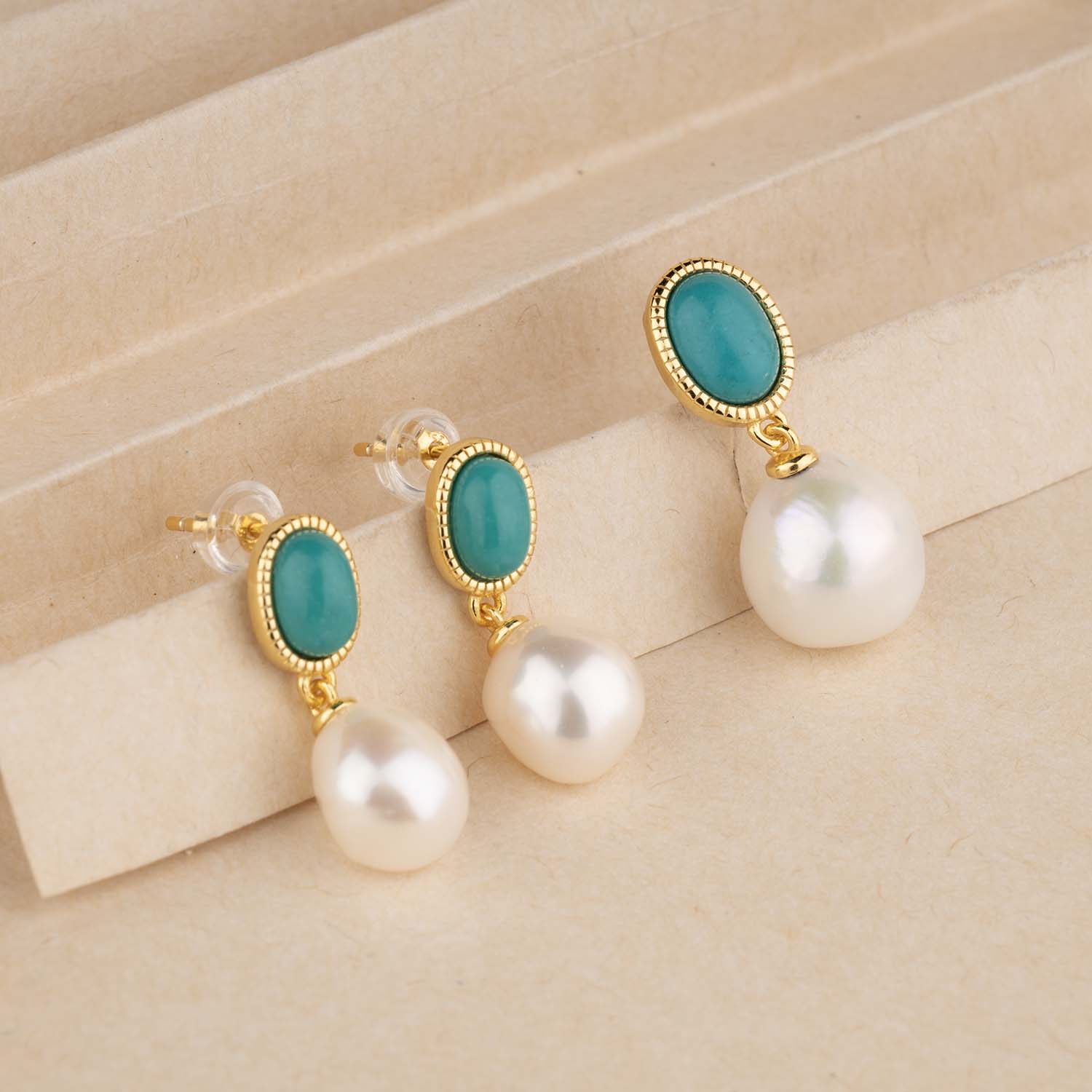 Pair of earrings with turquoise stones and pearls on a beige background
